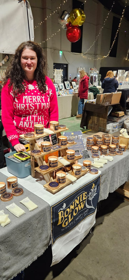 Emily at Bonnie Glow market stall displaying handmade Scottish candles